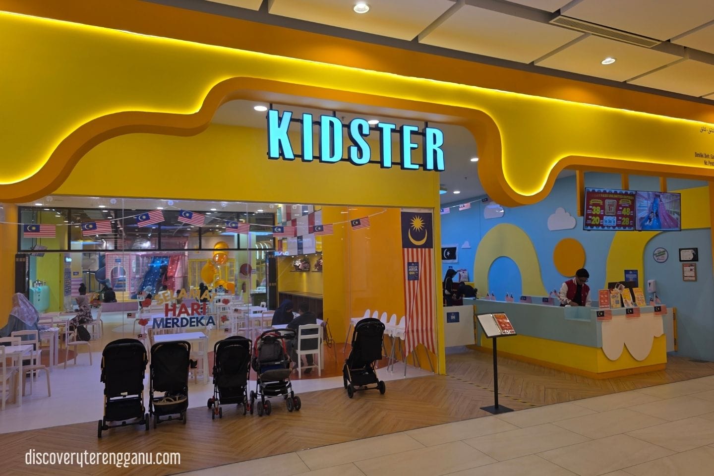 Pintu masuk Kidster di Mayang Mall dengan papan tanda kuning, kaunter tiket dan beberapa stroller di hadapan
