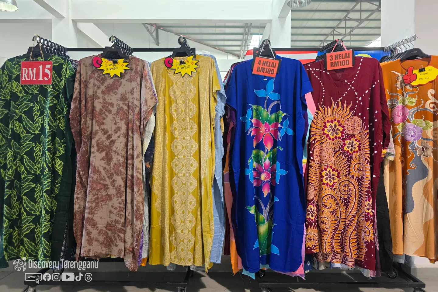 Deretan baju kelawar bercorak batik dan bunga tergantung pada rak di gerai pakaian Pasar Kedai Payang