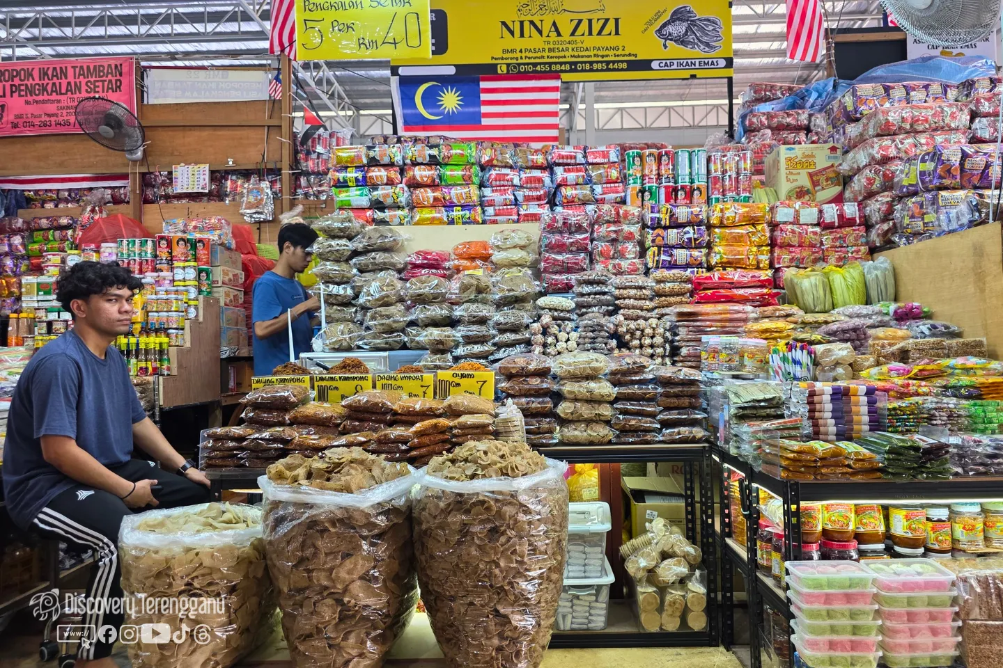 Kedai keropok, makanan ringan dan serunding di Pasar Kedai Payang 2 dengan bungkusan keropok bertimbun di kaunter dan rak barangan runcit di belakang
