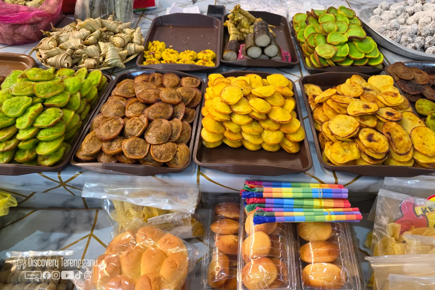 Dulang kuih tradisional termasuk apam berwarna hijau dan kuning, ketupat daun serta bahulu di gerai kuih dalam kawasan Pasar Kedai Payang