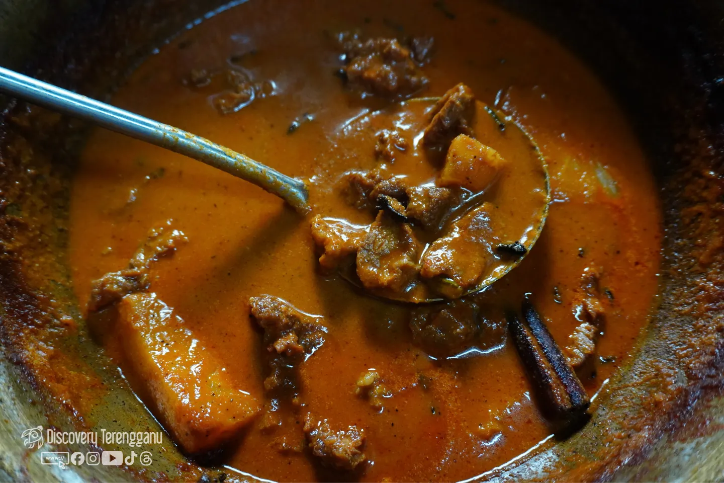 Pajeri nenas dalam periuk dengan senduk mengangkat daging dan nenas