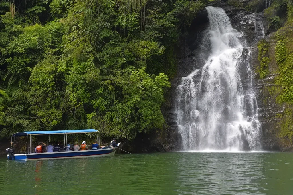 Ilustrasi AI bot pelancong berbumbung biru berhampiran air terjun di tepi hutan tasik