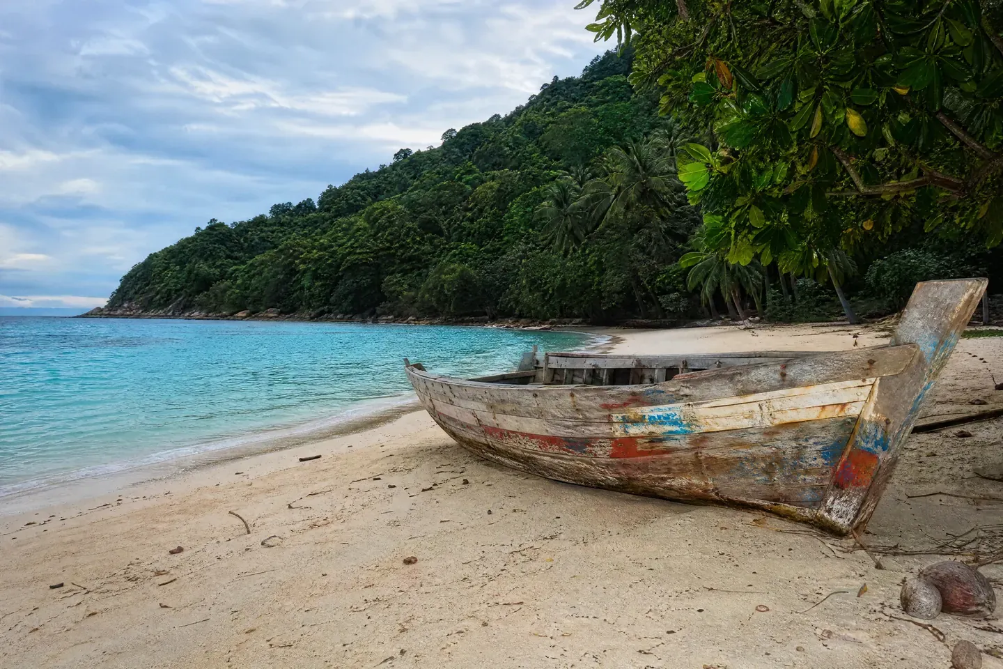 Ilustrasi AI: bot kayu lama yang usang di atas pasir putih sebuah pantai pulau tropika berbukit hijau